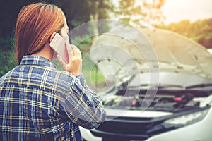 Young Woman calling for assistance with his car broken down by t