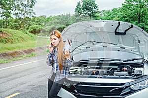 Young Woman calling for assistance with his car broken down by t