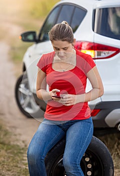 Young woman calling auto service to help her with broken car in field