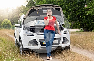 Young woman calling car service for help in field