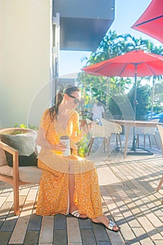 Young woman calling with cell phone while sitting in outdoor cafe at sunny day