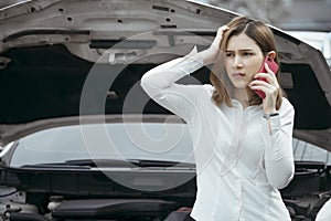 Young woman calling emergency help near broken car on road