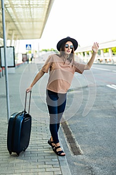 Young woman calling taxi, arriving at airport travelling alone