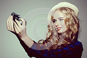 Young woman with camera. Blonde in a plaid shirt. Hipster fashion