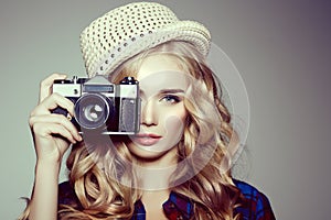 Young woman with camera. Blonde in a plaid shirt. Hipster fashion