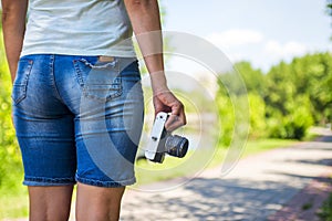 Young woman with camera outdoors . Soft sunny colors. woman with vintage retro camera