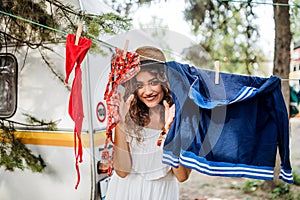 Young woman on camping holiday, hanging clothes on washing line.
