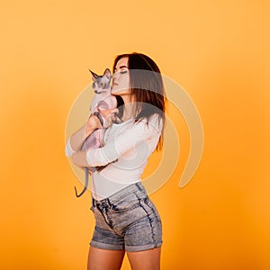 Young woman with canadian sphynx cat in studio, grey background