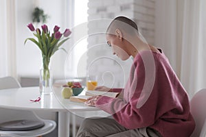 Young woman with cancer reading book, cancer awareness concept.