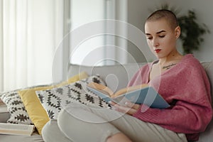 Young woman with cancer reading book, cancer awareness concept.