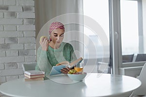 Young woman with cancer reading book, cancer awareness concept.