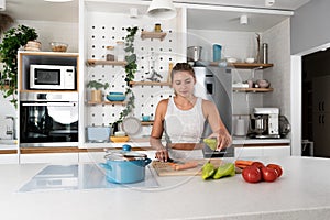 Young woman cancer survivor cooking and preparing vegetarian meal after long heavy sickness. Vegan female in the kitchen making