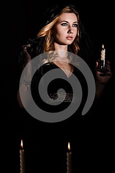 Young woman with a candle in darkness