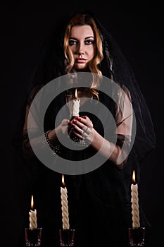 Young woman with a candle in darkness