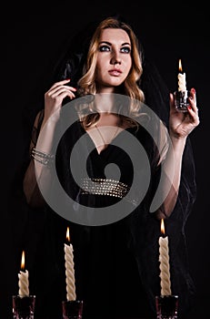 Young woman with a candle in darkness