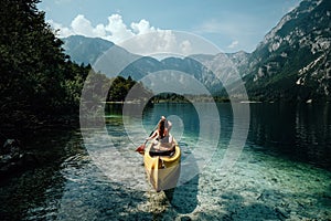 Young woman canoeing in the lake bohinj on a summer day