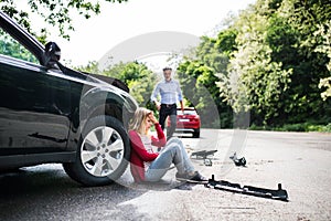 Young woman by the car after an accident and a man running towards her.