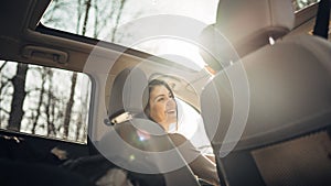 Young woman in a car,female driver looking at the passenger and smiling.Enjoying the ride,traveling,road trip concept.Driver