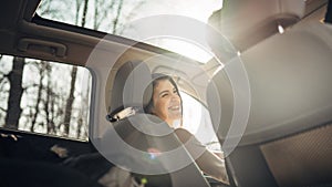 Young woman in a car,female driver looking at the passenger and smiling.Enjoying the ride,traveling,road trip concept.Driver