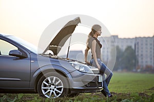 Young woman and a car with popped hood. Transportation, vehicles problems and breakdowns concept