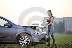 Young woman and a car with popped hood. Transportation, vehicles problems and breakdowns concept