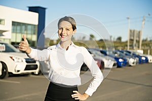 Young woman car rental in front of garage with cars on the background