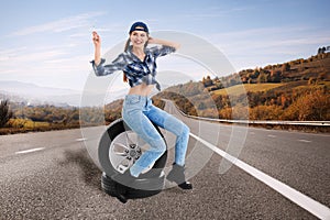 Young woman with car tires on asphalt road