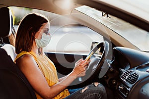 Young woman in a car using mobile phone, wearing protective mask. Summer season. prevention corona virus concept