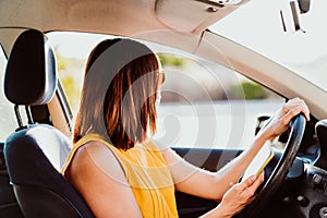 Young woman in a car using mobile phone, wearing protective mask. Summer season. prevention corona virus concept