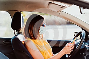 Young woman in a car using mobile phone, wearing protective mask. Summer season. prevention corona virus concept