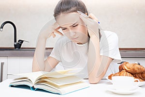 Young woman carefully reads a book, thinks, focused