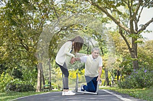 young woman caregiver is helping disability senior man fall due to practice walking with a walker