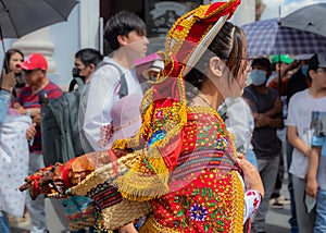 A young woman carries a basket of roasted guinea pig, Ecuador