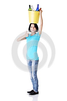 Woman carrying a bin with recyclable glass bottles.