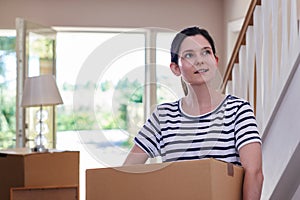 Young Woman Carrying Boxes Into New Home On Moving Day