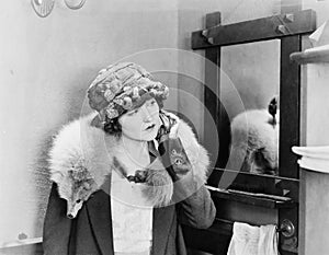 Young woman carrying a fox stole on her shoulders and adjusting her earring