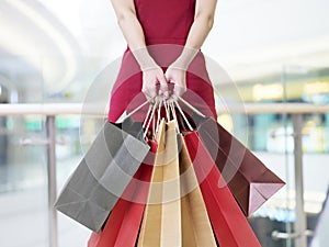 Young woman carrying paper shopping bags in modern mall