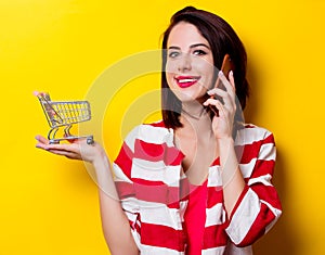 Young woman with cart and mobile phone