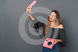 Young woman casual studio  on gray with retro telephone trying to make selfies