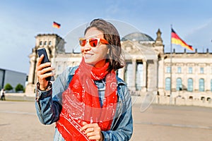 Young woman in casual wear communicating by her mobile internet phone at the Bundestag, Berlin