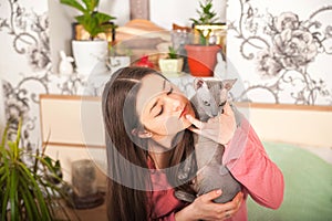 Young woman with cats having fun in the bedroom. Stay home concept. The girl with the cat Sphinx and Scottish Fold plays on the be