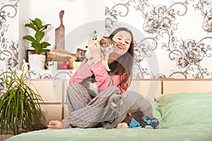 Young woman with cats having fun in the bedroom. Stay home concept. The girl with the cat Sphinx and Scottish Fold plays on the be