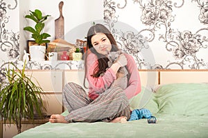 Young woman with cats having fun in the bedroom. Stay home concept. The girl with the cat Sphinx and Scottish Fold plays on the be