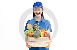 Young woman caucasian grocery delivery courier man in blue uniform with grocery wooden box with fresh fruit and vegetable.