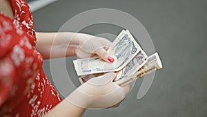 Young woman caught up in the tokyo city hustle, hands busy counting stacks of yen banknotes amidst the beautiful architecture of