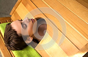 Young woman in cedar barrel. Spa and medical  procedures and treatment