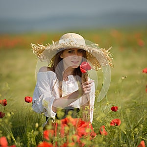 Young woman on cereal field with poppies in summer