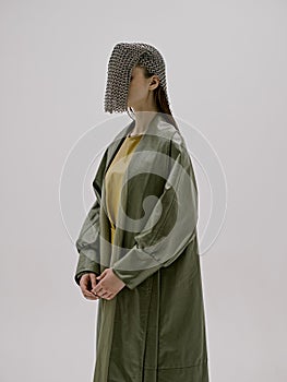 young woman chain mail on the face leather green coat luxury light background