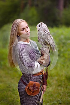 Young woman in chain mail looks an owl