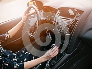 Young woman changing gears in car. Driving a car.